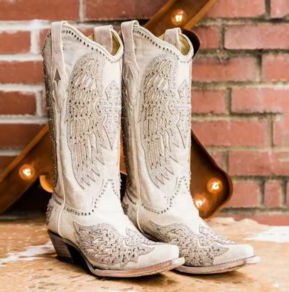 Cream-colored, bejeweled wing-embroidered, pointed-toe, mid-heeled, western-style cowboy boots for women are ideal for a chic everyday fashion look.